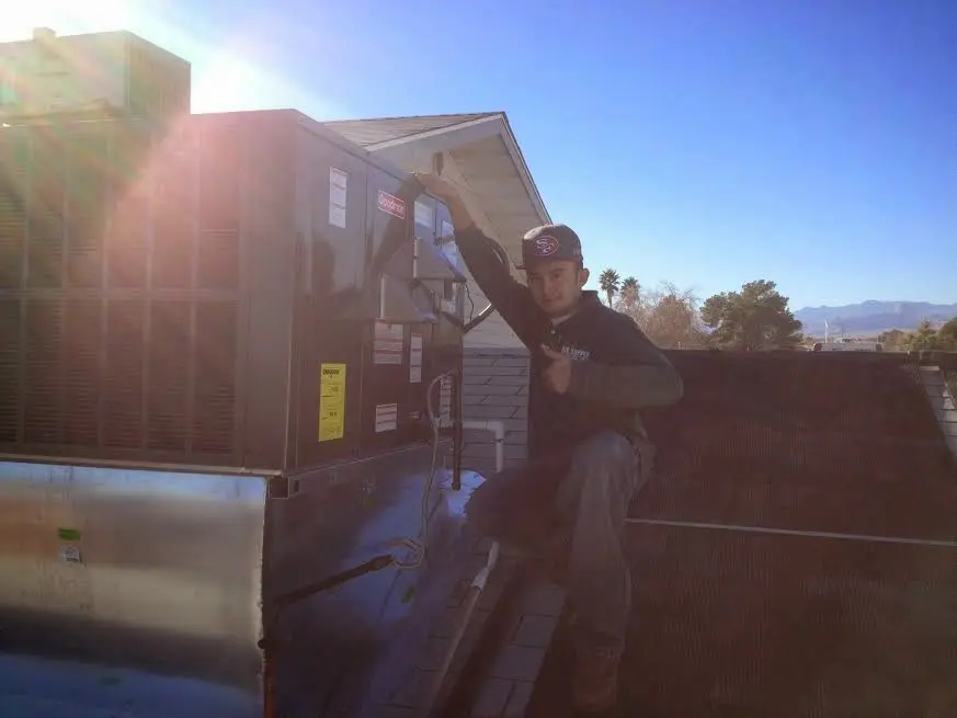 HVAC technician performing AC Tune-Up on a rooftop unit in Hanford