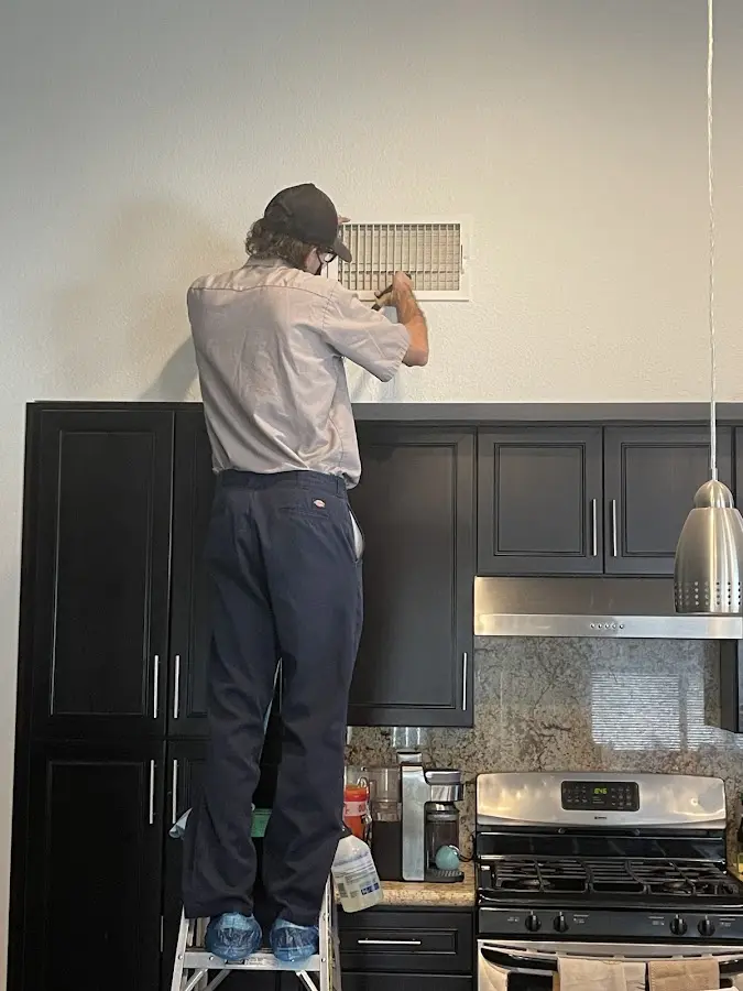 Technician inspecting an air vent during HVAC service in Hanford